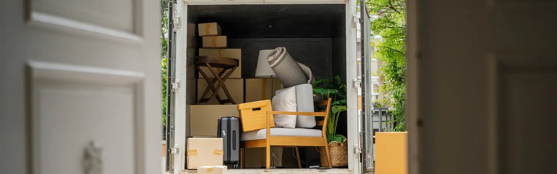 Impresa di pulizie Antonella Sgombero locali Sgombero Cantine, Solai, Garage. Camion di fronte alla porta di entrata di una casa con il retro aperto e riempito di svariati oggetti come sedie, tappeti valigie e scatoloni