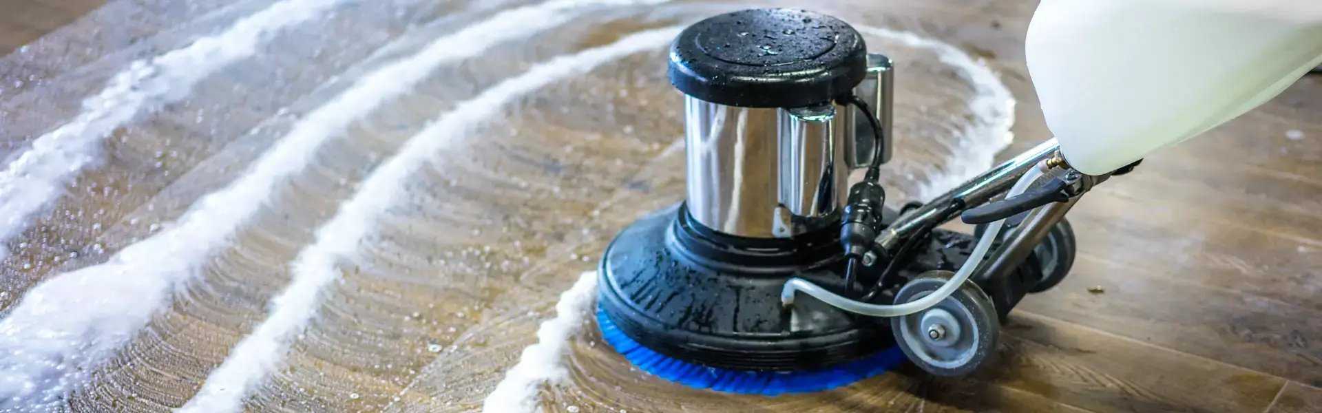 Impresa di pulizie AntonellaTrattamento superfici in marmo, legno, pietra. Macchinario con spazzola blu circolare in primo piano che sta trattando un pavimento in legno